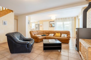 A living room with a black leather sofa, a brown leather couch, and a wooden coffee table. - Holiday Home 'Grande Maison À 5min Des Plages' with Shared Pool, Terrace and Private Garden (Pouldreuzic)