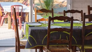 A dining table set with plates, cutlery, and a glass, surrounded by wooden chairs. - Holiday Home 'Grande Maison À 5min Des Plages' with Shared Pool, Terrace and Private Garden (Pouldreuzic)