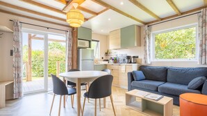 Eine moderne Küche mit Mikrowelle, Kühlschrank und Holzschränken. Es gibt einen Essbereich mit einem runden Tisch und Stühlen, sowie ein Sofa im Wohnbereich.