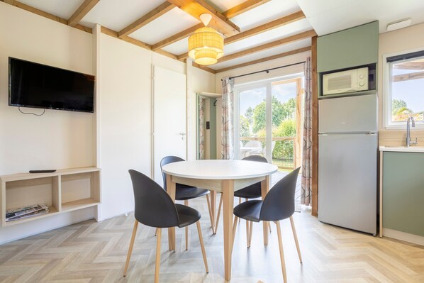 A modern kitchen with a built-in microwave, a refrigerator, and a dining area with a round table and four chairs.