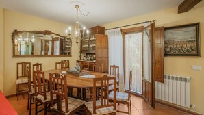 Un comedor con una mesa y sillas de madera, un candelabro, un espejo grande y una ventana con cortinas.