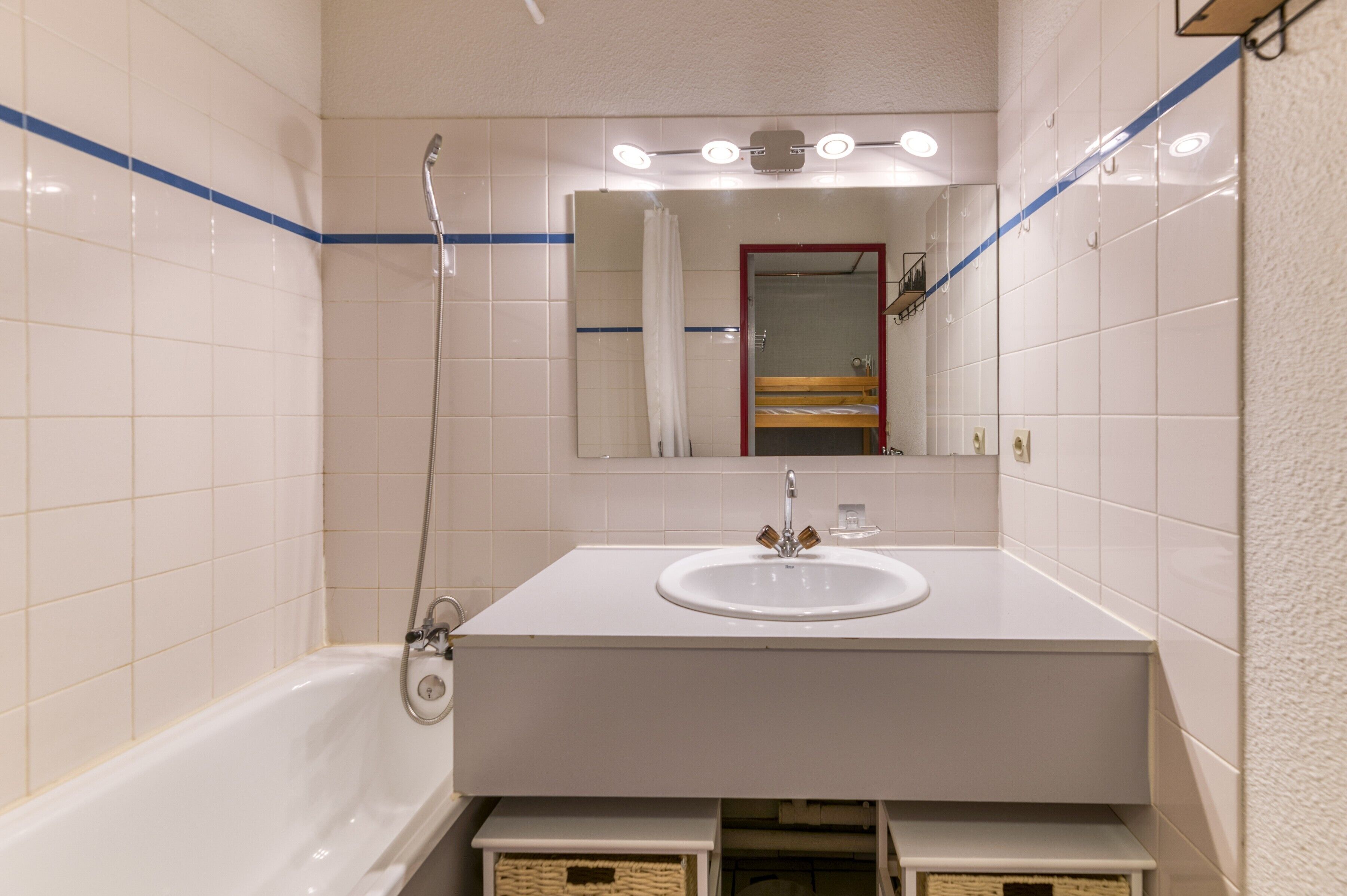 Een badkamer met een wit wastafelmeubel, een badkuip, een douche en een spiegel.