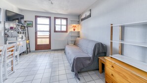 A small, well-lit room with a sofa, a wooden table, a lamp, and a TV. - Apartment 'Granges 9 - Vue' with Mountain View and Balcony (Villard-Reculas)