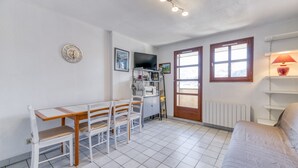 A compact room with a dining table, chairs, a sofa, a television, and a window with a view. - Apartment 'Granges 9 - Vue' with Mountain View and Balcony (Villard-Reculas)