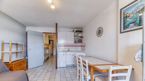 A compact kitchen with white cabinets, a dining table with chairs, and a wooden dresser. - Apartment 'Granges 9 - Vue' with Mountain View and Balcony (Villard-Reculas)