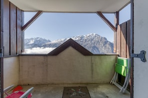 Een kamer met uitzicht op met sneeuw bedekte bergen, een houten plafond en een deur met een groen voorwerp ernaast.
