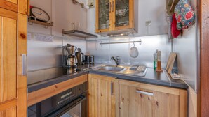 Una cocina con armarios de madera, electrodomésticos de acero inoxidable, un lavamanos doble y una estantería para colgar ollas.