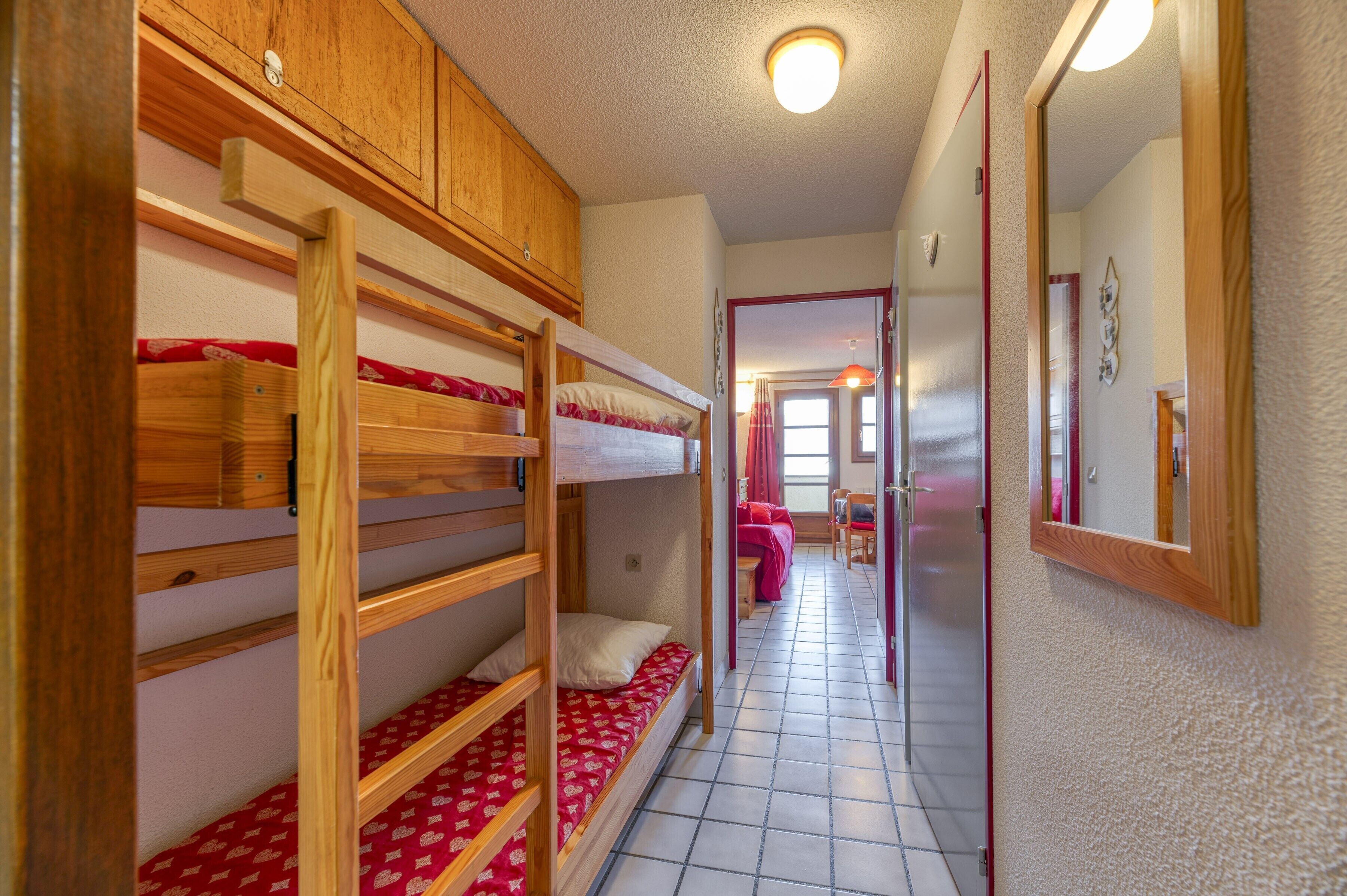 A corridor with bunk beds, a mirror, and a door leading to a room.