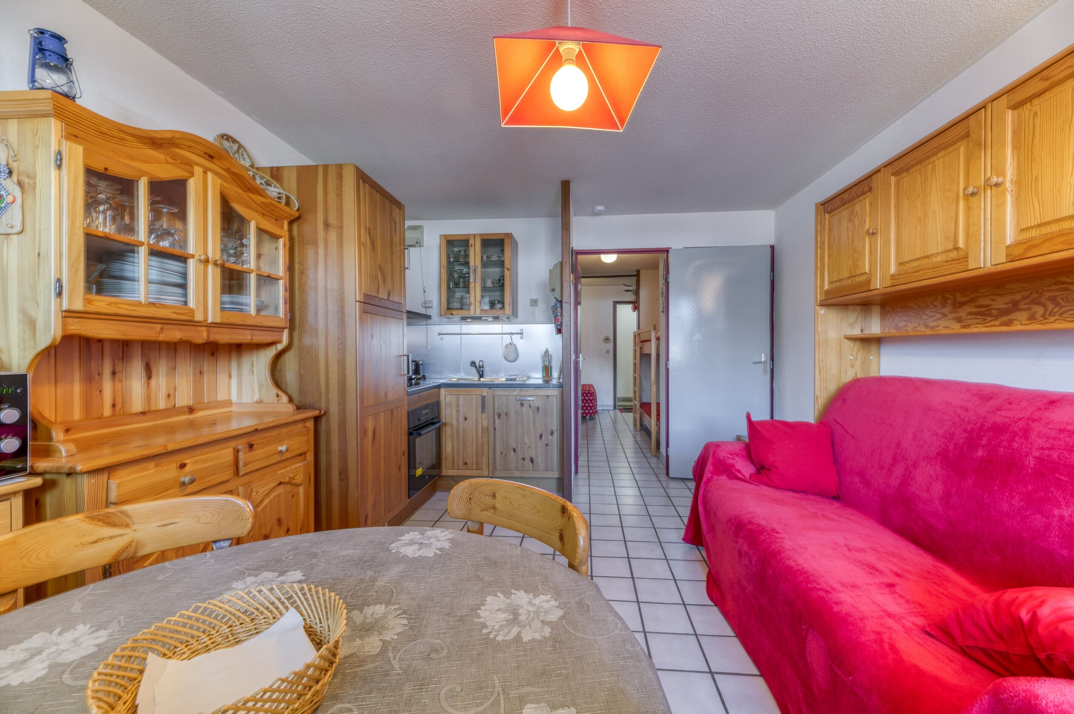 A compact living space with a dining area, a kitchenette, and a red sofa.