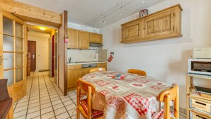 Eine Küche mit Holzausstattung, einem Esstisch mit gemustertem Tischläufer und einer Mikrowelle.