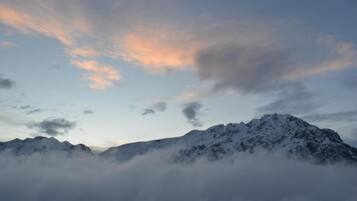A mountain range with snow-covered peaks and clouds at the base.