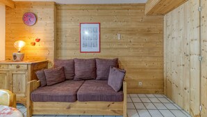Ein Holzhütten-Interieur mit einer Holzdirektiva, einer Uhr, einem gerahmten Bild und einem kleinen Tisch mit einer Lampe.