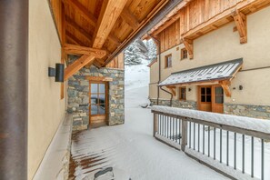 A snow-covered pathway leading to a wooden building with stone accents and a balcony with a metal railing. - Apartment 'Klochette - Charme Et Famille' with Mountain View, Private Terrace and Wi-Fi (Villard-Reculas)