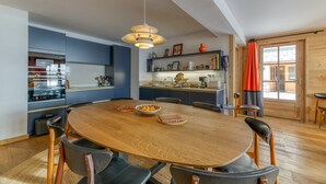 Una cocina moderna con una mesa de madera, sillas y una lámpara colgante.