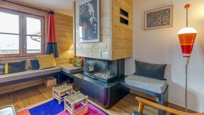 Una sala de estar acogedora con chimenea, paredes de madera y una ventana con cortinas.