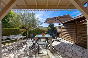 An outdoor patio with a table and chairs, a bench, and a pergola with a patterned top.