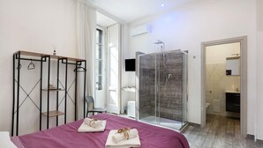 A hotel room with a bed, a shower, a wardrobe, and a bathroom. - Room 'Al Corso Suite' with Balcony, Wi-Fi and Air Conditioning (Salerno)