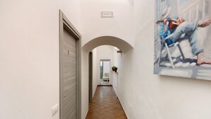 A hallway with a tiled floor, a white door, a white wall, and a painting. - Room 'Al Corso Suite' with Balcony, Wi-Fi and Air Conditioning (Salerno)