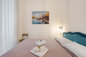 A hotel room with a bed, a painting of a cityscape, a bedside table, and a nightstand. - Room 'Al Corso' with Wi-Fi and Air Conditioning (Salerno)