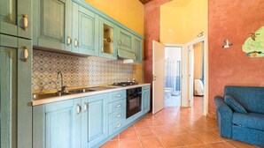 A kitchen with teal cabinets, a patterned backsplash, and a tiled floor.