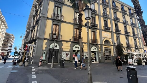 Un edificio de varios pisos con balcones, una palmera y cielo despejado.