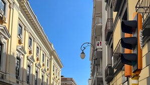 Una calle con edificios, una señal de no estacionamiento y una persona con una maleta.