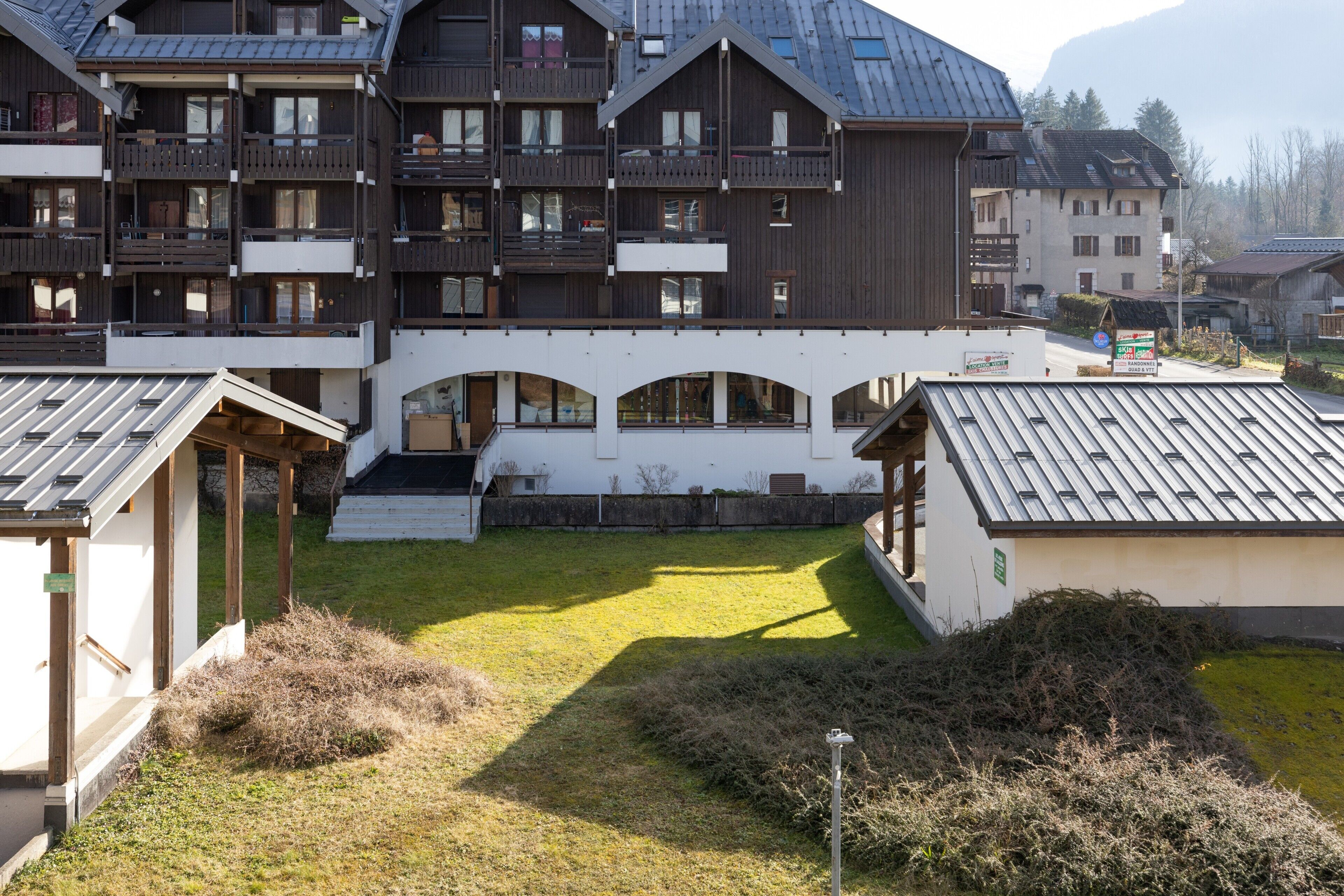 Un immeuble à plusieurs étages doté de balcons, d’une cour intérieure et d’un petit jardin.