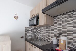 A kitchen with a microwave, sink, and tiled backsplash.