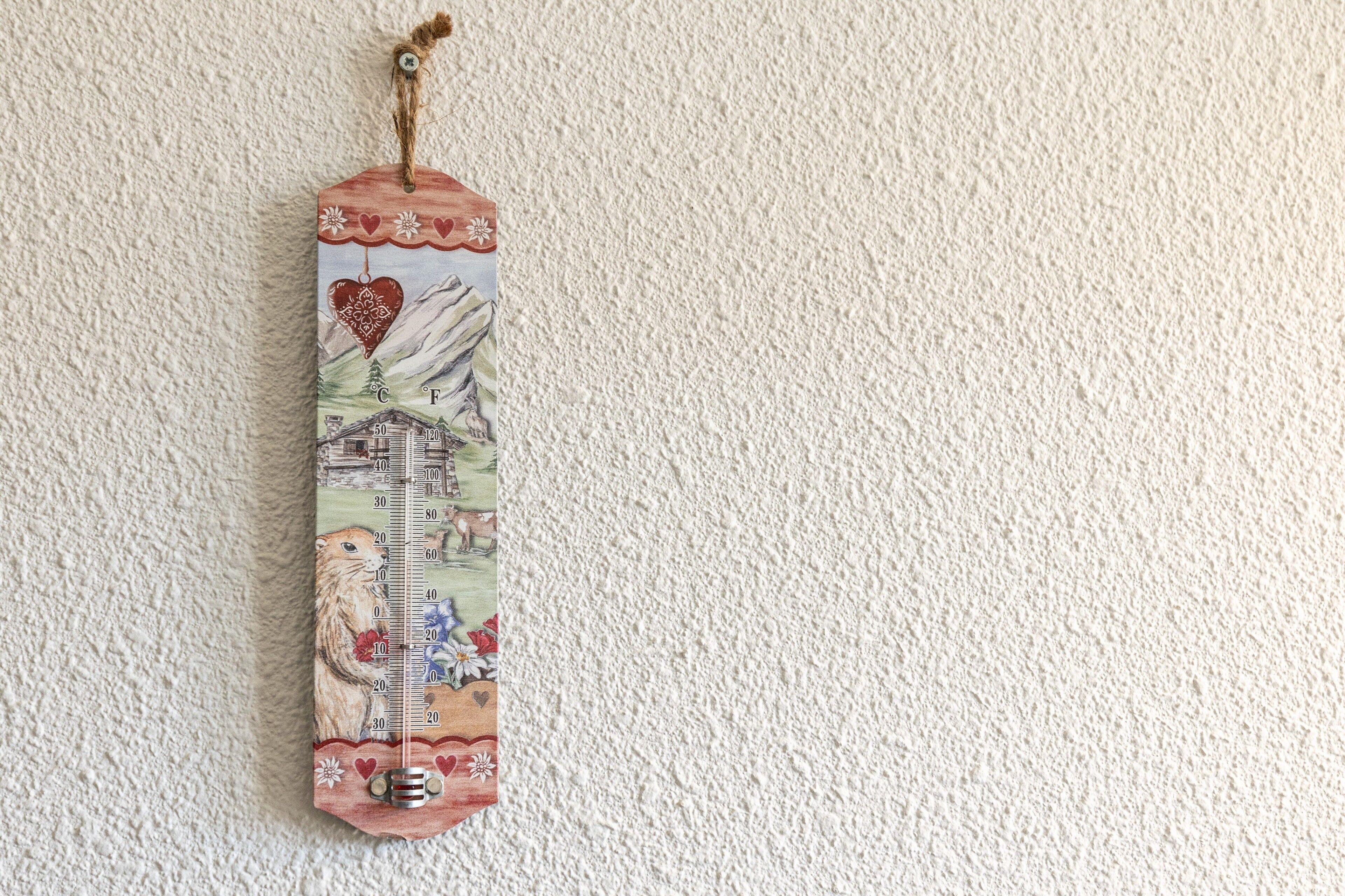 Un termómetro con diseño de casa, montaña y corazón.