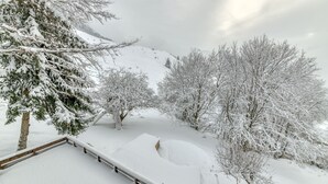 Een besneeuwd landschap met bomen en een houten omheining.