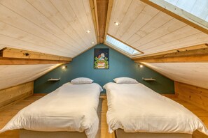 Quarto com duas camas, vigas de madeira no teto e um domo de vidro, além de um quadro na parede.
