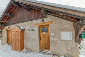 A rustic building with a wooden door marked 'Le Floeon,' a small window, and a wooden staircase leading to the entrance. - Chalet 'Le Flocon Grand  4 Étoiles' with Mountain View, Private Terrace and Wi-Fi (Villard-Reculas)