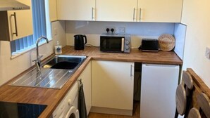Une cuisine compacte équipée d’un évier, d’un four à micro-ondes, d’un grille-pain et d’un petit réfrigérateur.