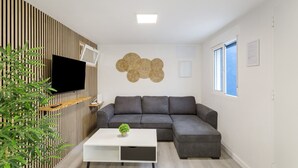 A modern living room with a sectional sofa, a flat-screen TV, a white coffee table, and a decorative wall piece. - Vacation Home 'Magma' with Private Terrace, Private Garden and Wi-Fi (Santa Brígida)