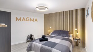 A modern bedroom with a bed, a wall-mounted fan, a bedside table with a lamp, and a wall with vertical wooden slats. - Vacation Home 'Magma' with Private Terrace, Private Garden and Wi-Fi (Santa Brígida)