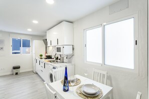 A modern kitchen with white cabinets, a microwave, and a dining area with a table set for two.