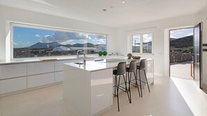 Una cocina moderna con ventanas amplias, una isla central, taburetes de bar y vistas a montañas.