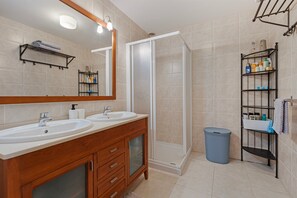 Ein Badezimmer mit zwei Waschbecken, einem Spiegel, einer Dusche und Ablageflächen.