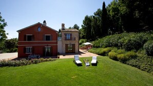 Une maison à deux étages avec un patio, une pelouse et un jardin.