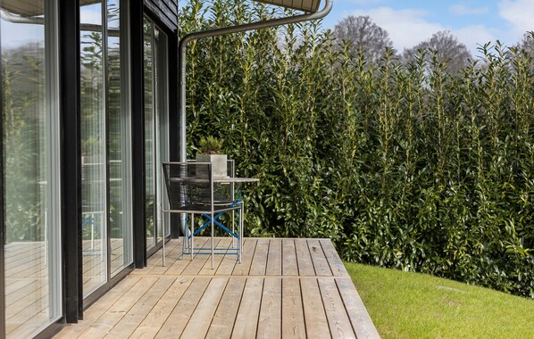 A wooden deck with a metal chair and a small table, overlooking a dense hedge. - Awesome home in Aabenraa with WiFi (Aabenraa)