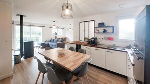 Una cocina moderna con una mesa de comedor de madera, sillas grises y un horno empotrado.