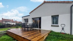 Una casa moderna con terraza de madera y mobiliario exterior.