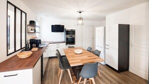 Una cocina moderna con una mesa de comedor de madera, sillas negras y armarios blancos.