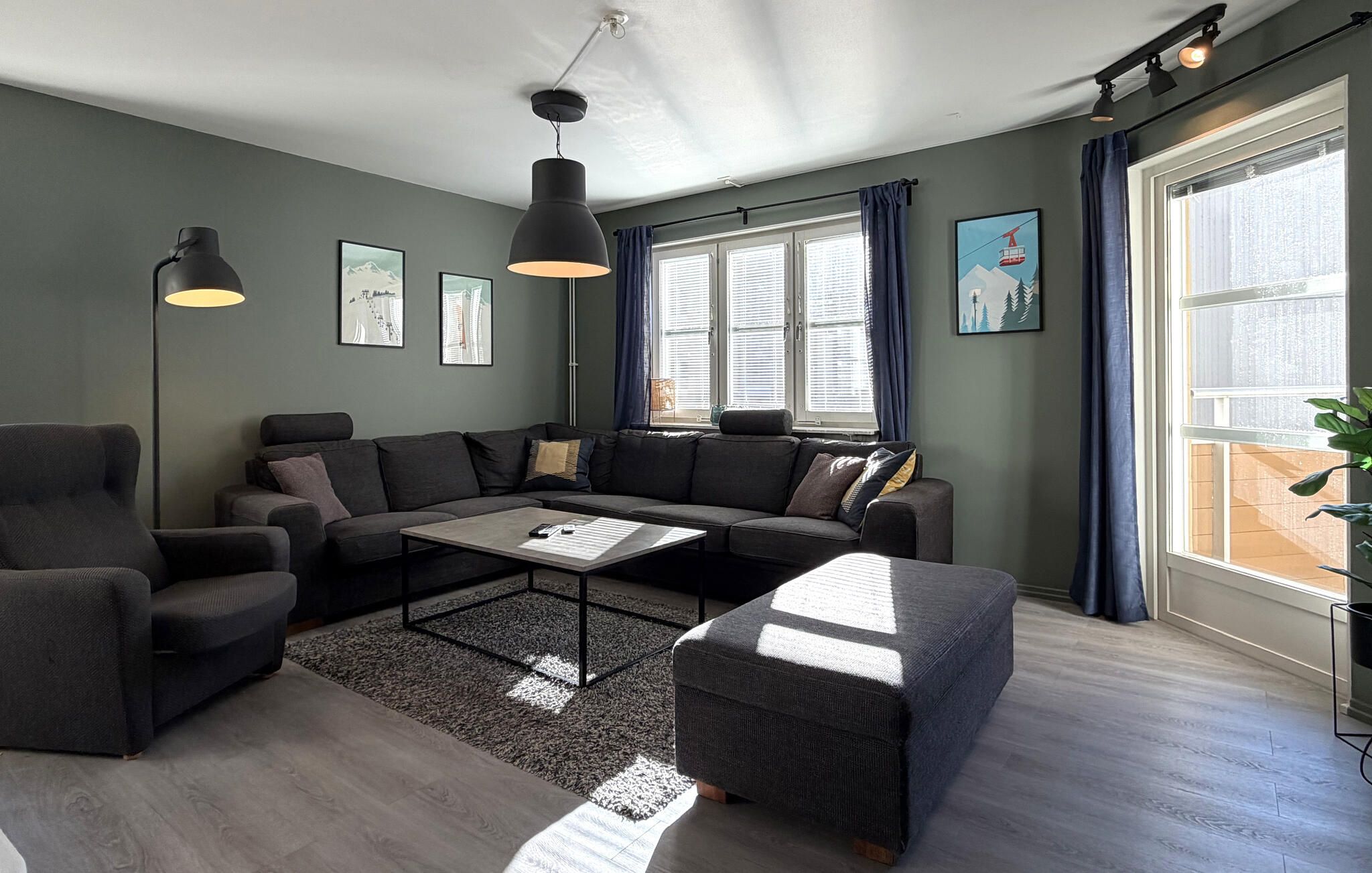 Un salon moderne avec un canapé d’angle, une table basse et une grande fenêtre agrémentée de rideaux.
