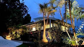 Ein modernes Haus, umgeben von üppiger tropischer Vegetation, darunter Palmen und Farne.
