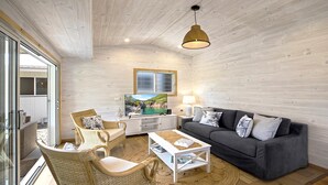 Una sala de estar acogedora con un sofá, dos sillones, una mesita de centro, un televisor y un ventanal con vistas panorámicas.