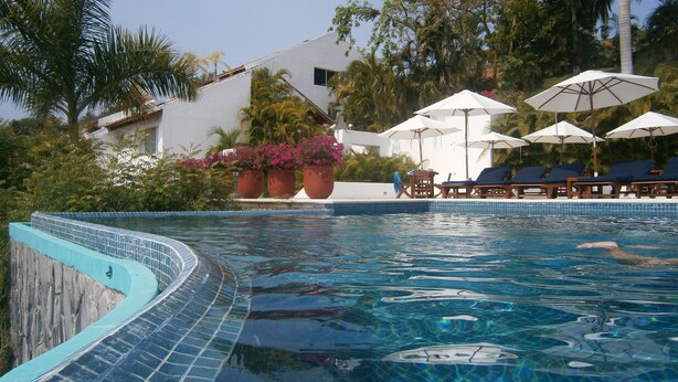 Een zwembad met helderblauw water, omringd door ligbedden en parasols.