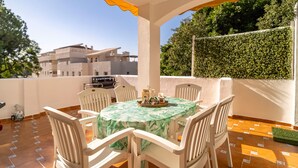 Un patio con mesa y sillas, una parrilla y vistas a edificios y follaje.