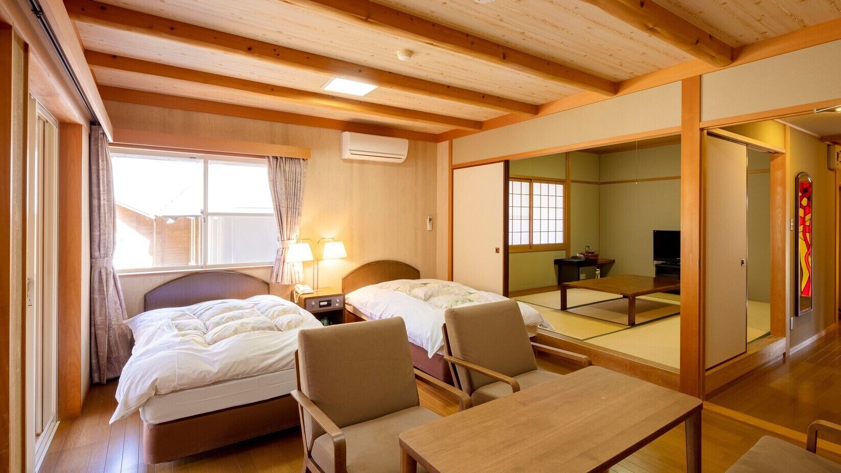 A traditional Japanese-style room with two beds, a small table, and a television.