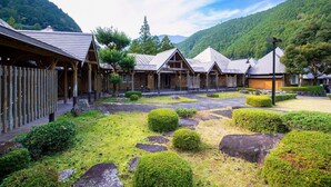 Ein traditionelles japanisches Ryokan mit Holzbauten und einem Garten mit Steinen und Büschen.